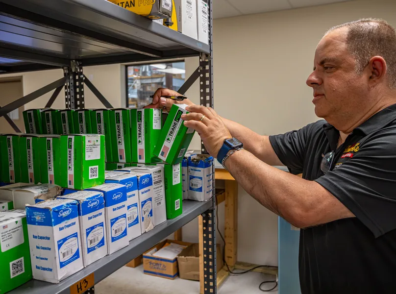 Wentzel's team member pulling a boxed capacitor from the parts shelves at the Sarasota warehouse
