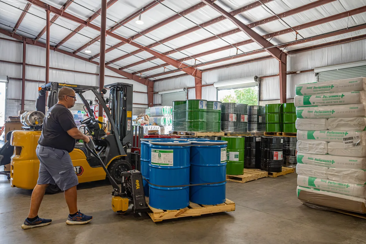 Wentzel's team member moving spray foam drums with a forklift in the Sarasota warehouse